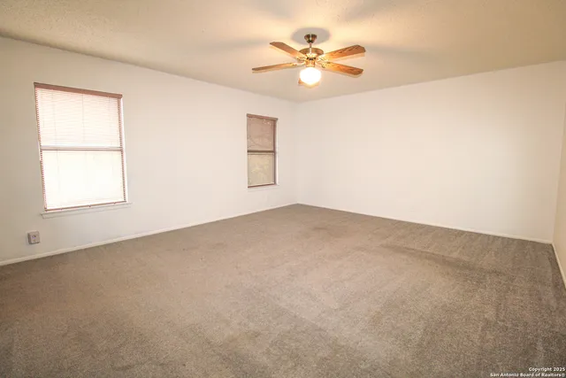 an empty room with windows and fan