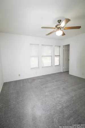 an empty room with windows and fan