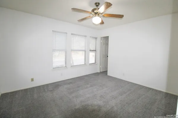 an empty room with a window and a fan