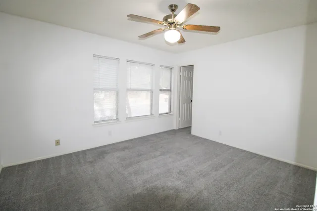 an empty room with a window and a fan