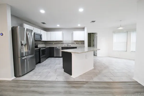 a kitchen with stainless steel appliances granite countertop a stove top oven a refrigerator and a sink