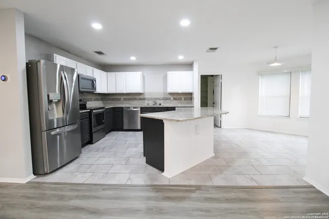 a kitchen with stainless steel appliances granite countertop a stove top oven a refrigerator and a sink