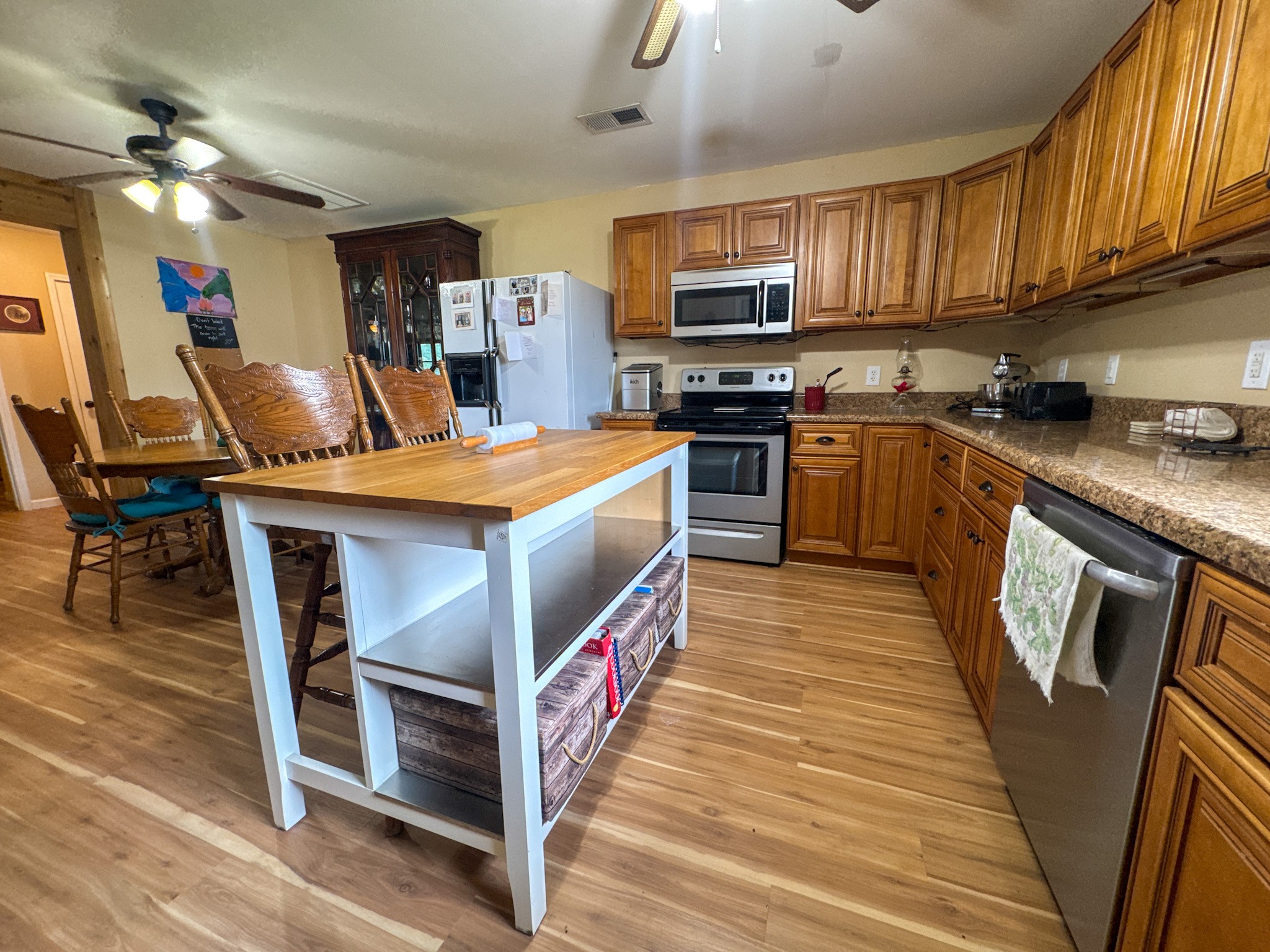 4791 Guys Chewalla Road Ramer, TN 38367 - Photo 28 of 77 a kitchen with stainless steel appliances granite countertop a stove top oven a sink dishwasher a dining table and chairs with wooden floor