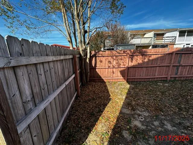 a view of backyard with barbeque grill wooden floor and a fence