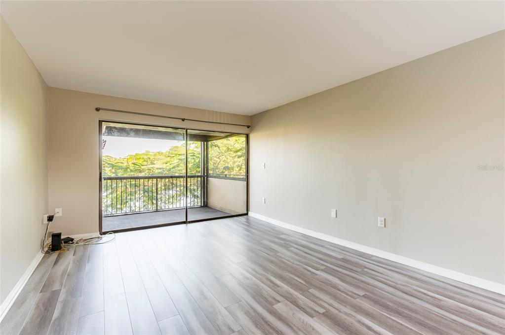 735 South Village Drive, Unit 206 St. Petersburg, FL 33716 - Photo 12 of 45 an empty room with wooden floor and windows