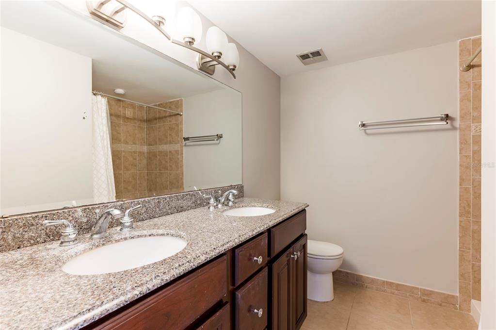 735 South Village Drive, Unit 206 St. Petersburg, FL 33716 - Photo 26 of 45 a bathroom with a granite countertop sink a toilet and a mirror
