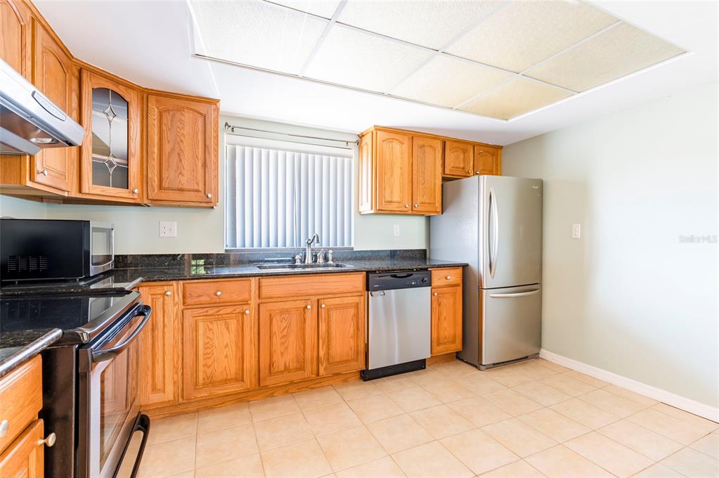 735 South Village Drive, Unit 206 St. Petersburg, FL 33716 - Photo 6 of 45 a kitchen with stainless steel appliances granite countertop a refrigerator a stove top oven and a sink