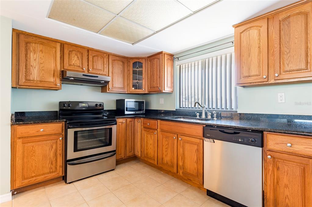 735 South Village Drive, Unit 206 St. Petersburg, FL 33716 - Photo 7 of 45 a kitchen with stainless steel appliances granite countertop a stove a sink and a refrigerator