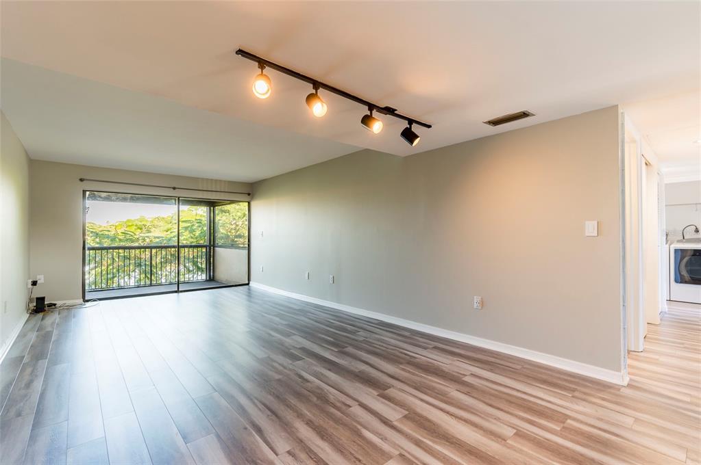 735 South Village Drive, Unit 206 St. Petersburg, FL 33716 - Photo 9 of 45 a view of an empty room with wooden floor and a window