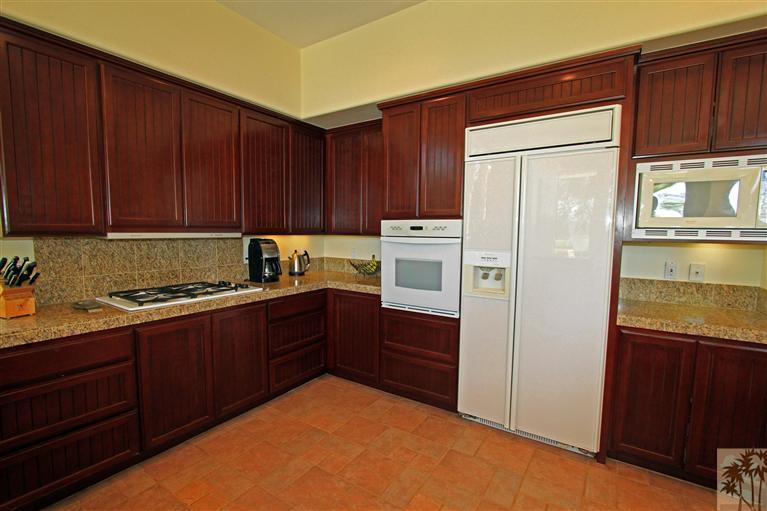 286 Loch Lomond Road Rancho Mirage, CA 92270 - Photo 13 of 24 a kitchen with granite countertop wooden cabinets and white appliances