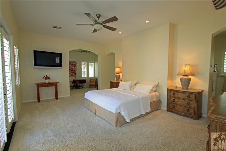286 Loch Lomond Road Rancho Mirage, CA 92270 - Photo 15 of 24 a spacious bedroom with a bed a mirror on dresser and a flat screen tv