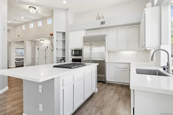 a kitchen that has a lot of white cabinets and wooden floor