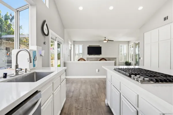 a kitchen with kitchen island granite countertop a sink and a stove top oven with wooden floor