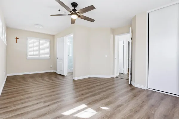 a view of an empty room with wooden floor and a window