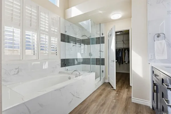 a bathroom with a tub a sink and a large window