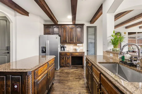 a kitchen with stainless steel appliances granite countertop a refrigerator a stove and a sink with wooden floor