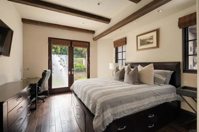 a bedroom with a bed a desk and chair with the wooden floor