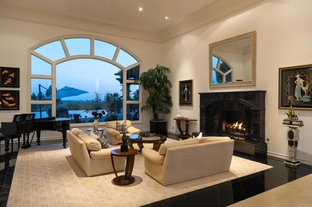 a living room with couches a fireplace and a dining table with a large window