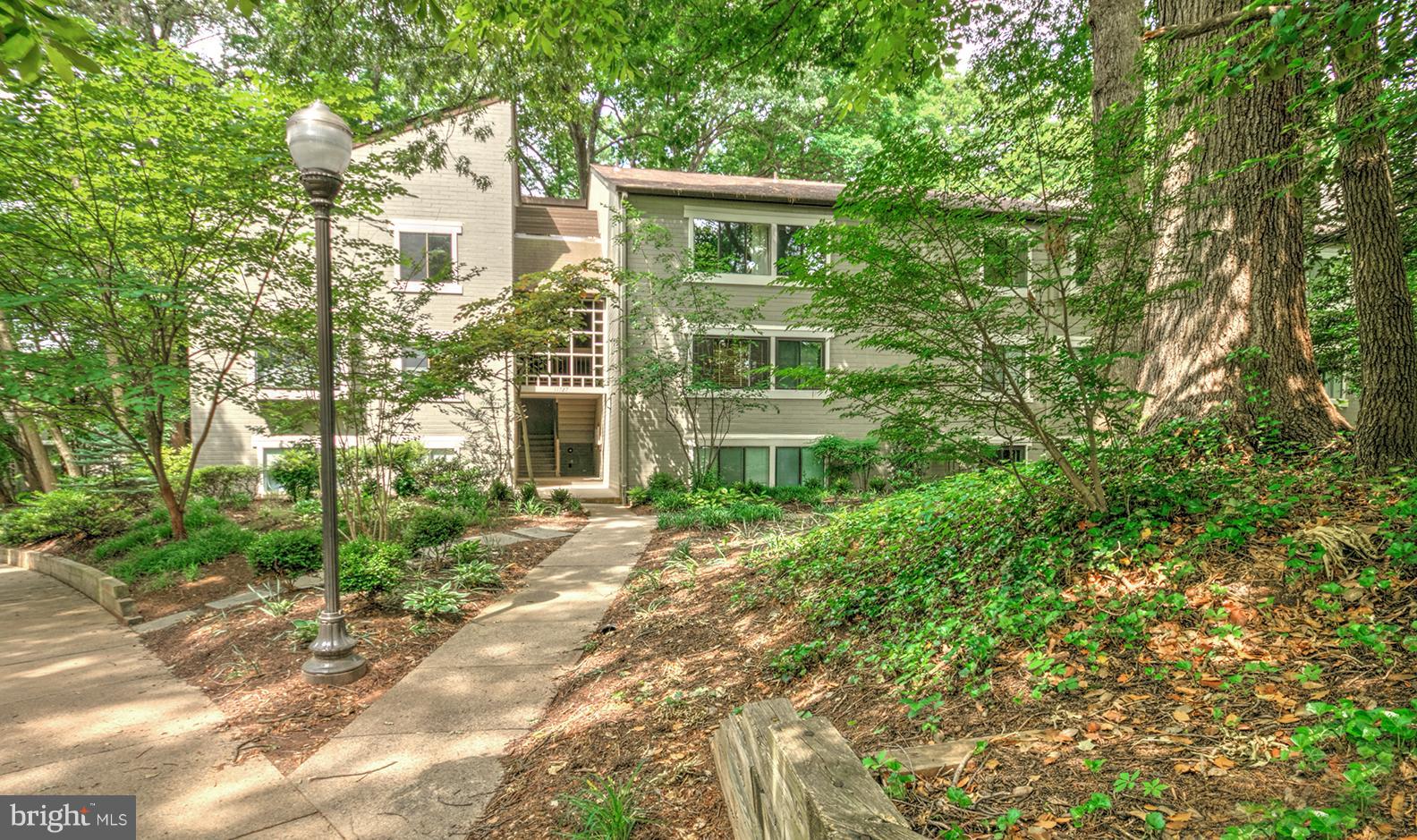11727 Ledura Court, Unit 201 Reston, VA 20191 - Photo 1 of 29 a view of a brick house with a yard and large trees