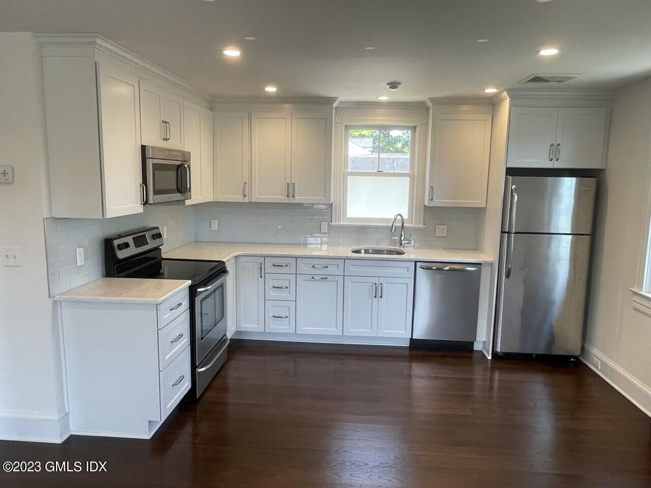 37 Orchard Street, Unit B Cos Cob, CT 06807 - Photo 5 of 15 a kitchen with stainless steel appliances granite countertop a refrigerator a sink dishwasher a stove and white countertops with wooden floor