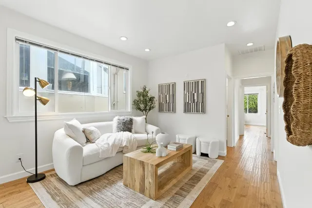 a kitchen with stainless steel appliances granite countertop a stove a sink dishwasher and white cabinets with wooden floor