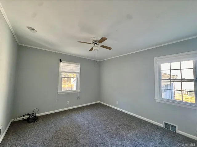 an empty room with windows and fan
