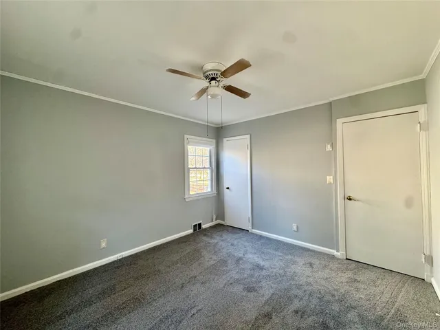 an empty room with a window and a ceiling fan
