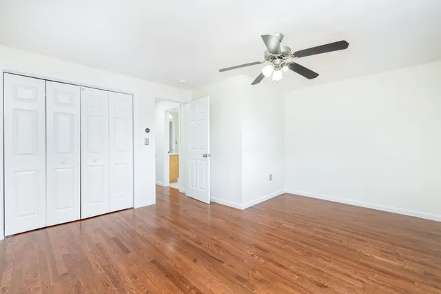 a view of a room with wooden floor and a ceiling fan