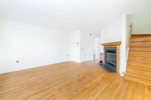 a view of empty room with wooden floor and fireplace