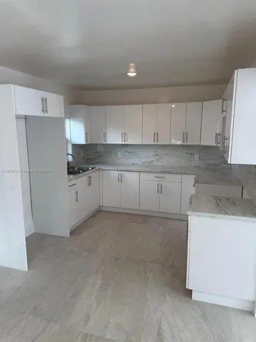a kitchen with white cabinets and refrigerator