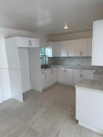 a kitchen with white cabinets and refrigerator