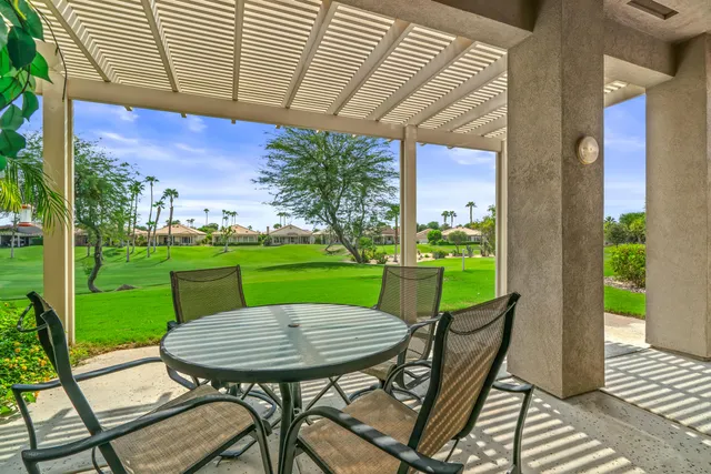 a view of a chairs and table in patio next to a yard