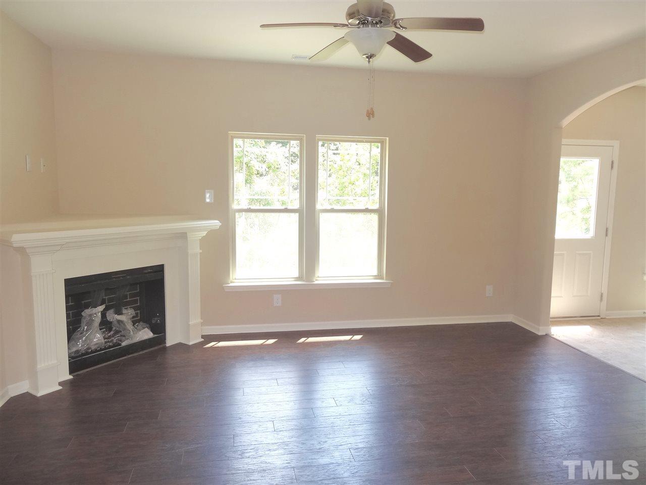 6212 Quitman Trail Raleigh, NC 27610 - Photo 12 of 20 an empty room with wooden floor fireplace and windows