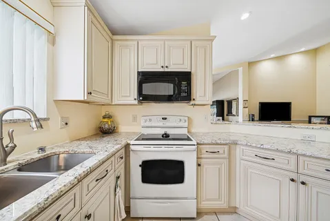 a kitchen with granite countertop white cabinets and white appliances