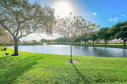 a swimming pool with lots of green space and trees in the background