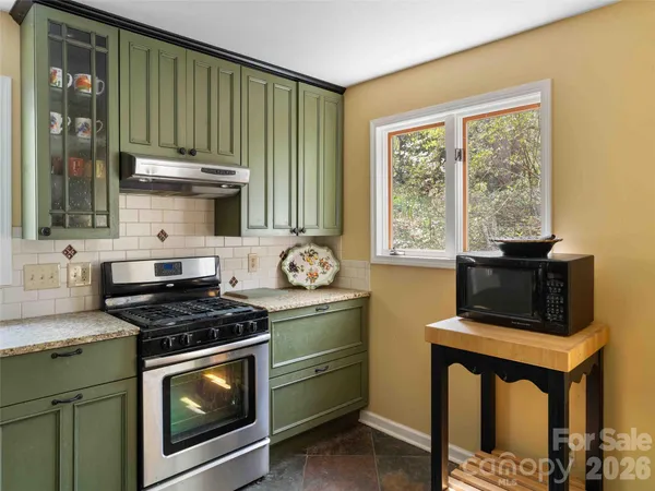 a kitchen with granite countertop a stove a sink and a microwave