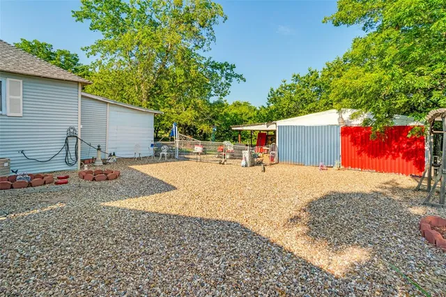 a view of a swimming pool with a yard and large trees