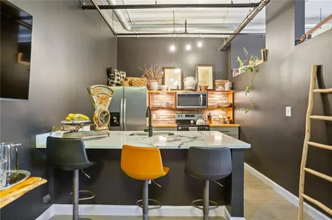 a kitchen with stainless steel appliances granite countertop a sink a stove and chairs