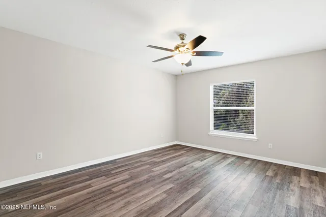 a view of a room with wooden floor and a ceiling fan