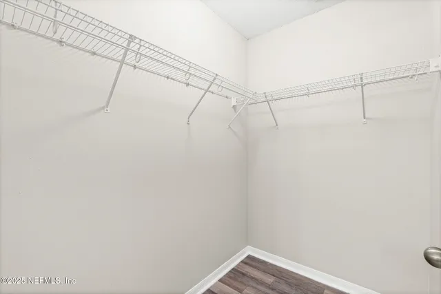 an empty room with wooden floor ceiling fan and windows