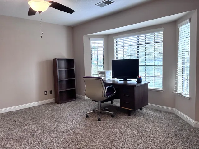 a view of a workspace with furniture and a window