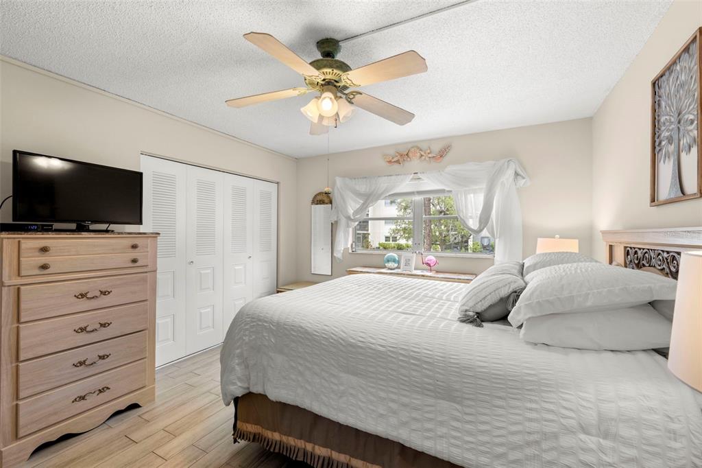 1370 Heather Ridge Boulevard, Unit 105 Dunedin, FL 34698 - Photo 15 of 56 a bedroom with a large bed a flat tv screen and a chandelier