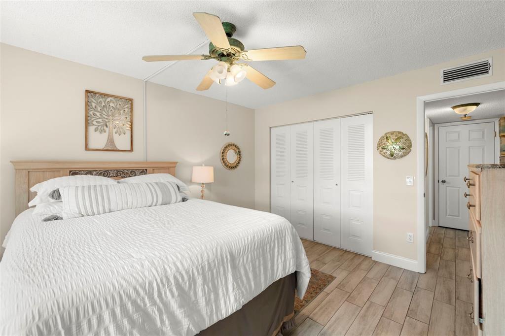 1370 Heather Ridge Boulevard, Unit 105 Dunedin, FL 34698 - Photo 17 of 56 a bedroom with a large bed and a ceiling fan