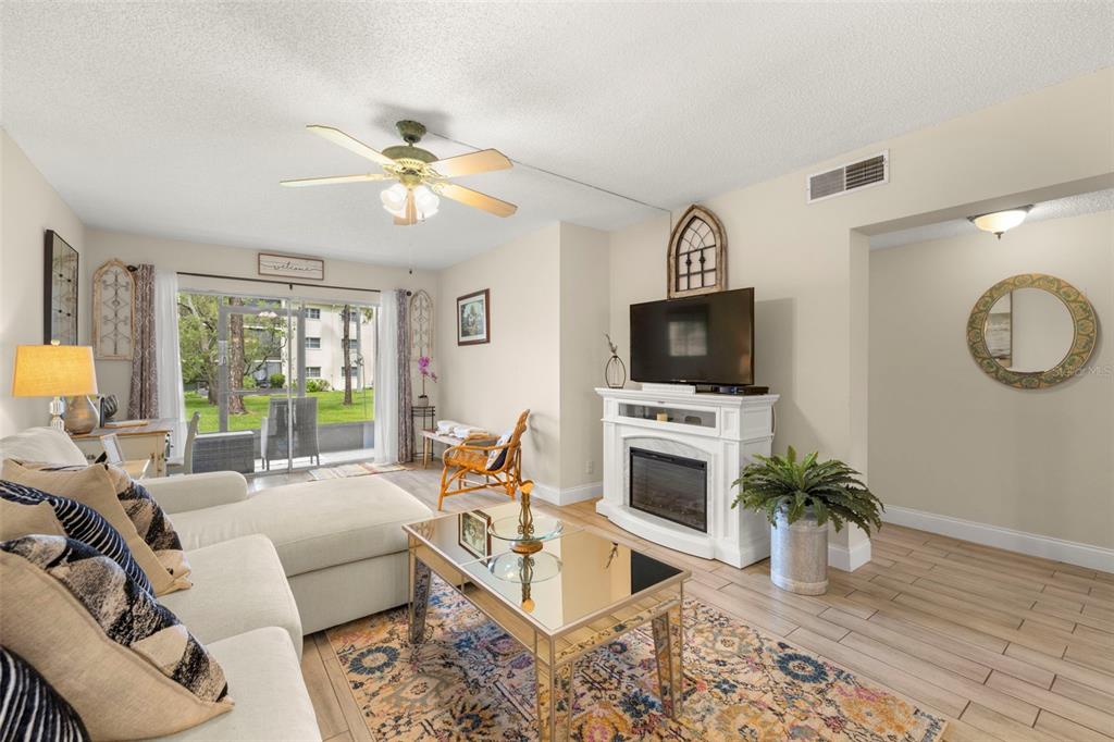 1370 Heather Ridge Boulevard, Unit 105 Dunedin, FL 34698 - Photo 4 of 56 a living room with furniture a flat screen tv and a fireplace