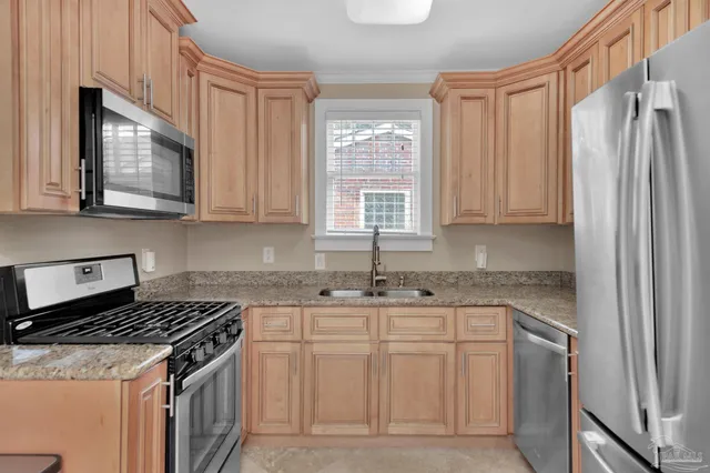 a kitchen with stainless steel appliances granite countertop a stove a sink and a microwave