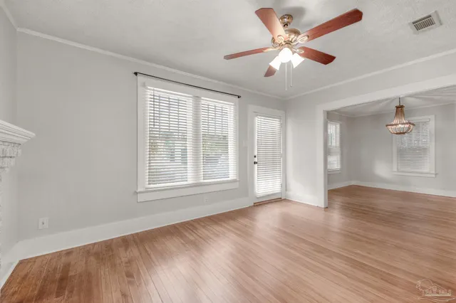 a view of an empty room with window and wooden floor