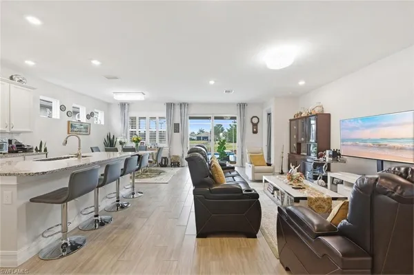 a living room with furniture kitchen view and large windows