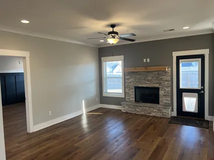 a view of an empty room with wooden floor fireplace and a window