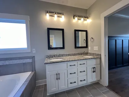 a bathroom with a granite countertop double vanity sink a mirror and a