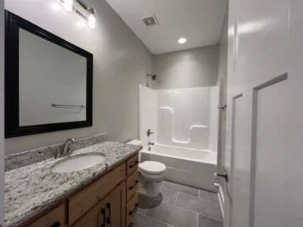 a bathroom with a granite countertop sink toilet and shower